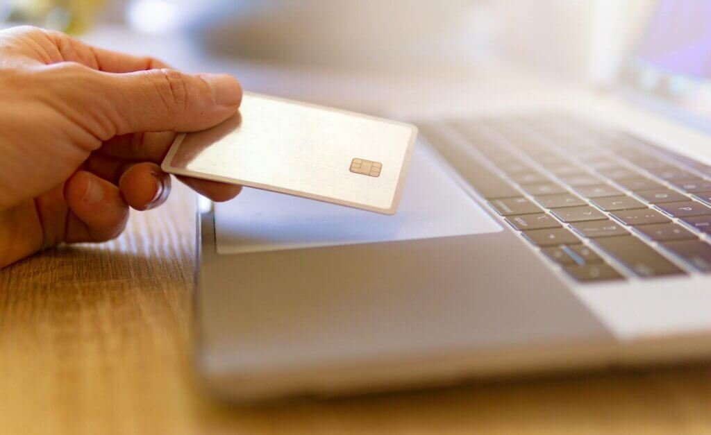 a hand holding white card on top of a laptop